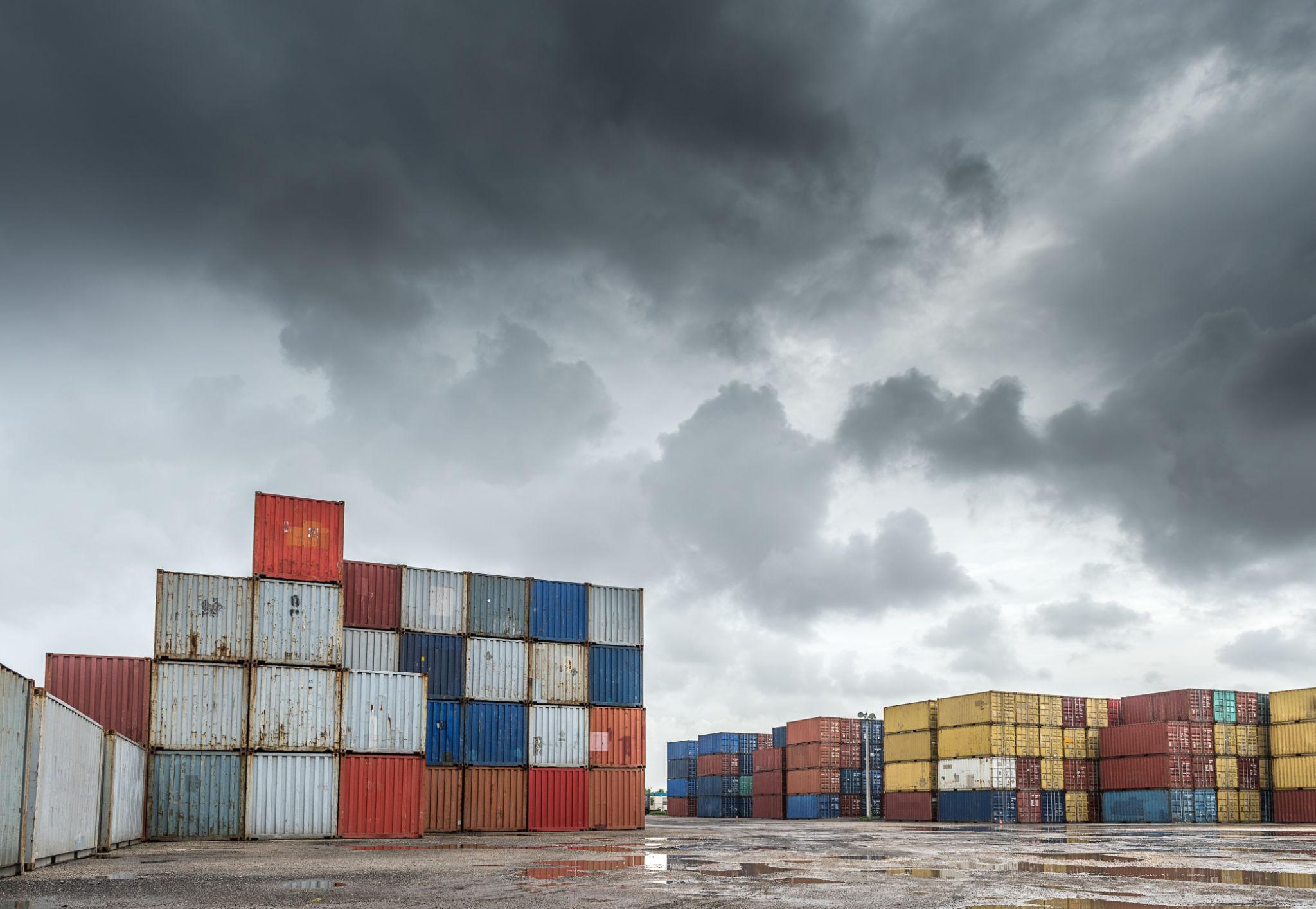 Shipping containers under storm clouds, representing governance under pressure